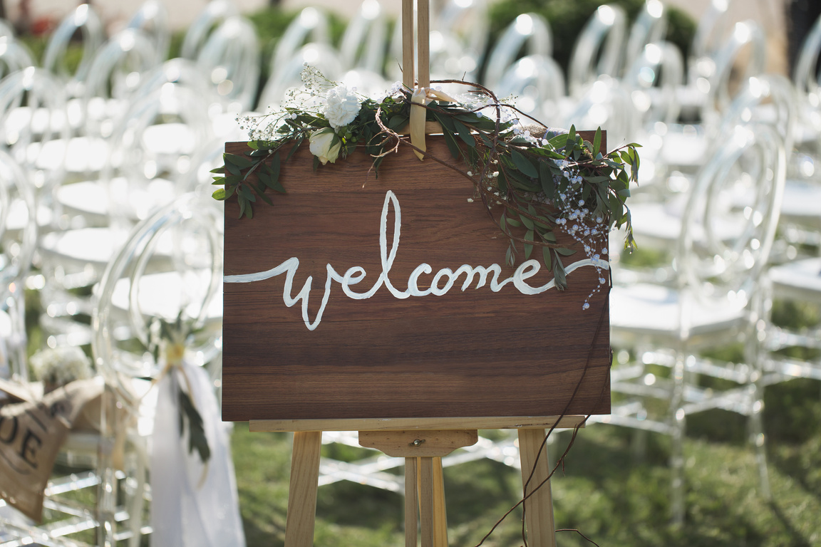 Romantic wedding ceremony on the beach. Sign welcome.